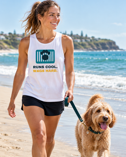 Smiling woman in a white Runs Cool. Wags Hard. singlet walking on the beach with her Labradoodle (AI-generated image)